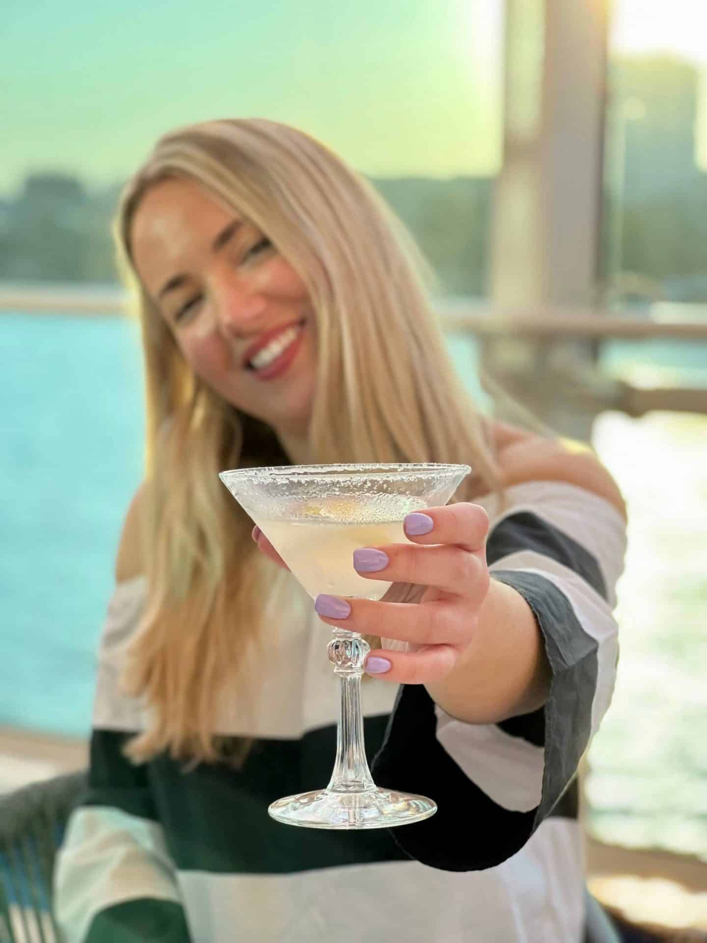 Woman holding up Margarita with purple nails 